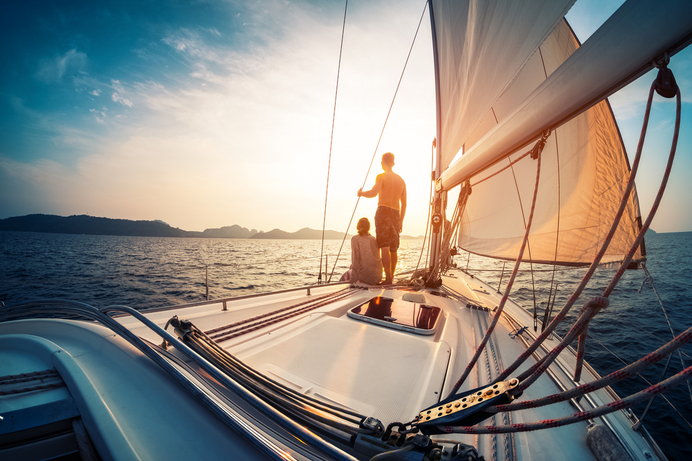 Couple,Enjoying,Sunset,From,The,Deck,Of,The,Sailing,Boat